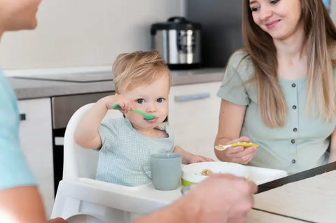 A Pair Of Parents Coaxing The Baby To Eat