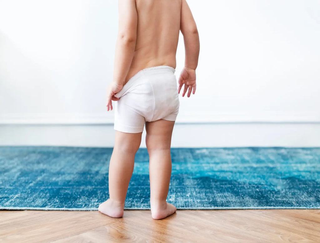 A baby boy pulling his diapers