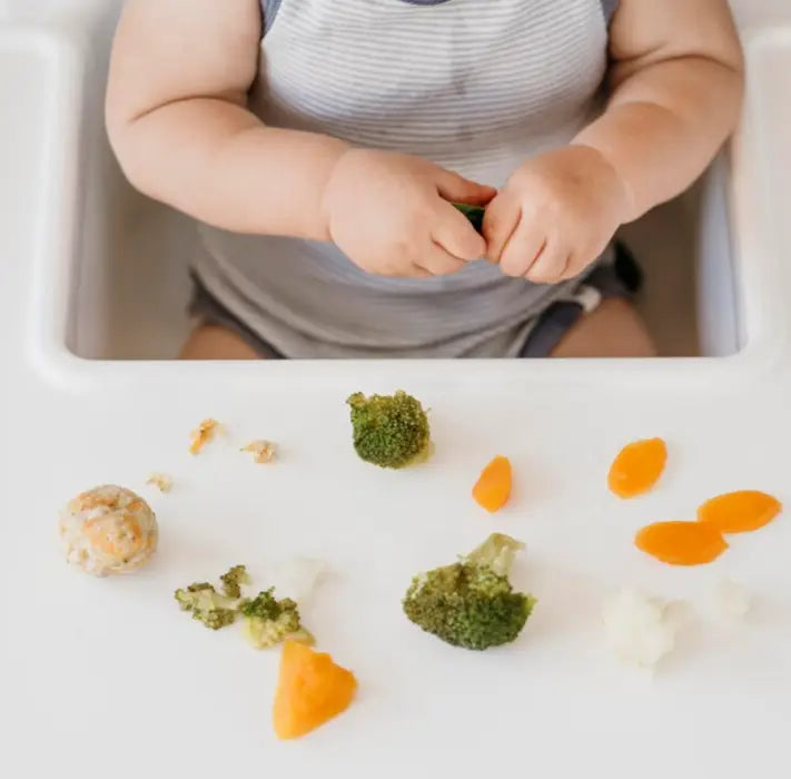 Baby Boy In Highchair Eating Vegetables Alone