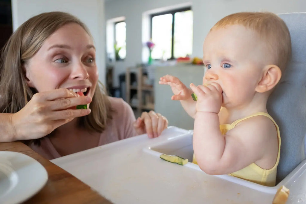 Happy excited mom training baby bite solid food