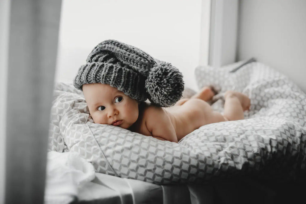 Naked newborn boy warm winter hat lies soft blanket