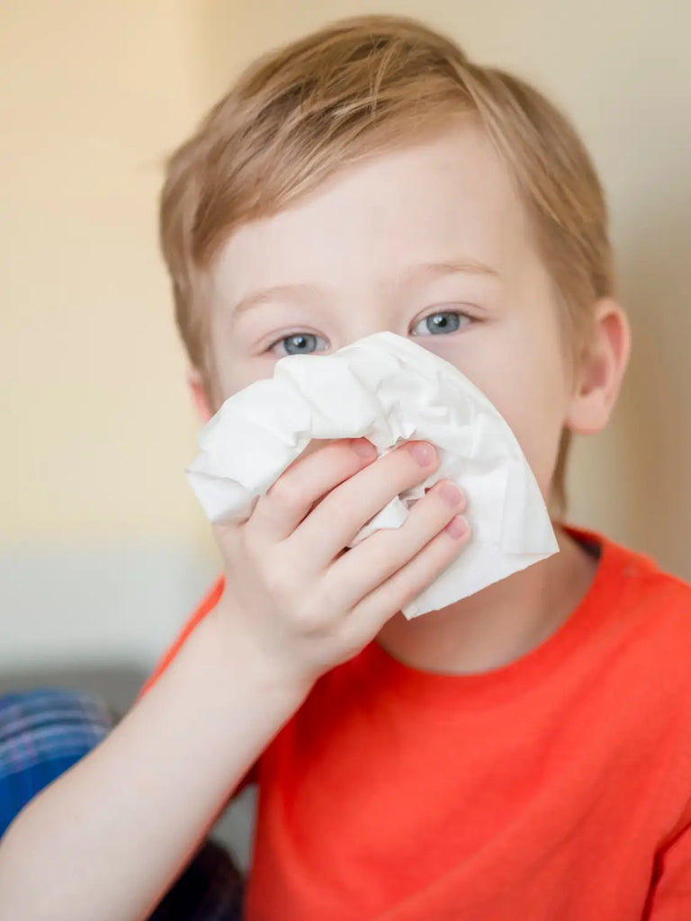 Young boy blowing his nose